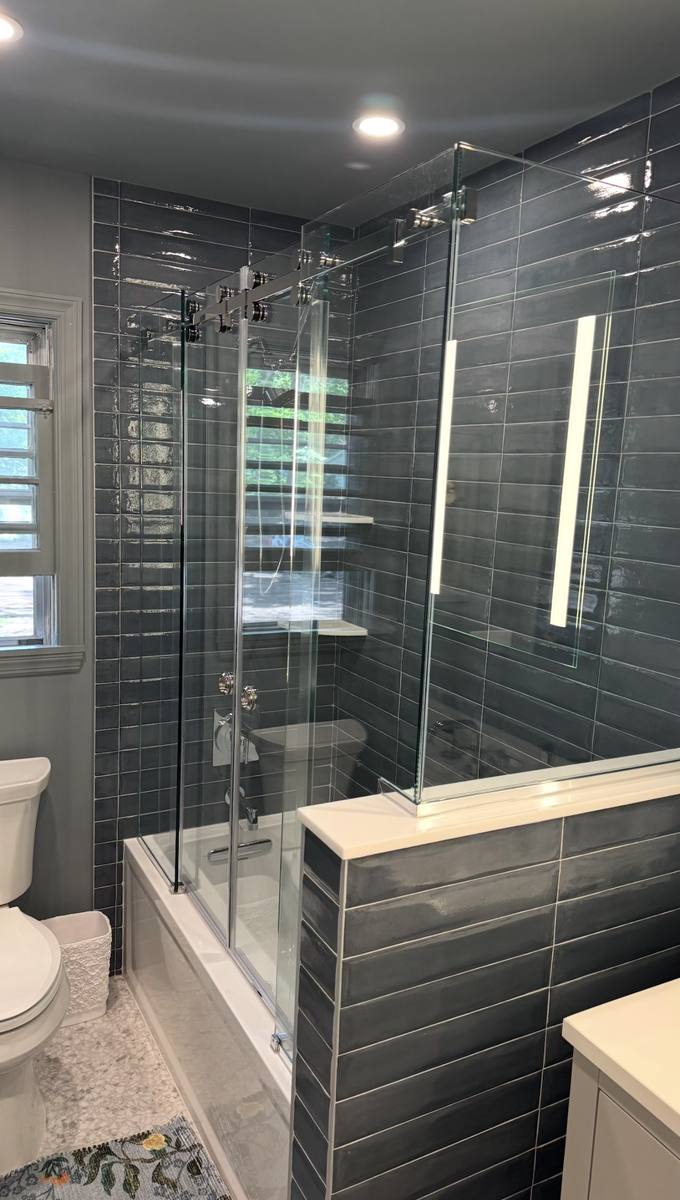 Frameless sliding glass tub enclosure with chrome hardware